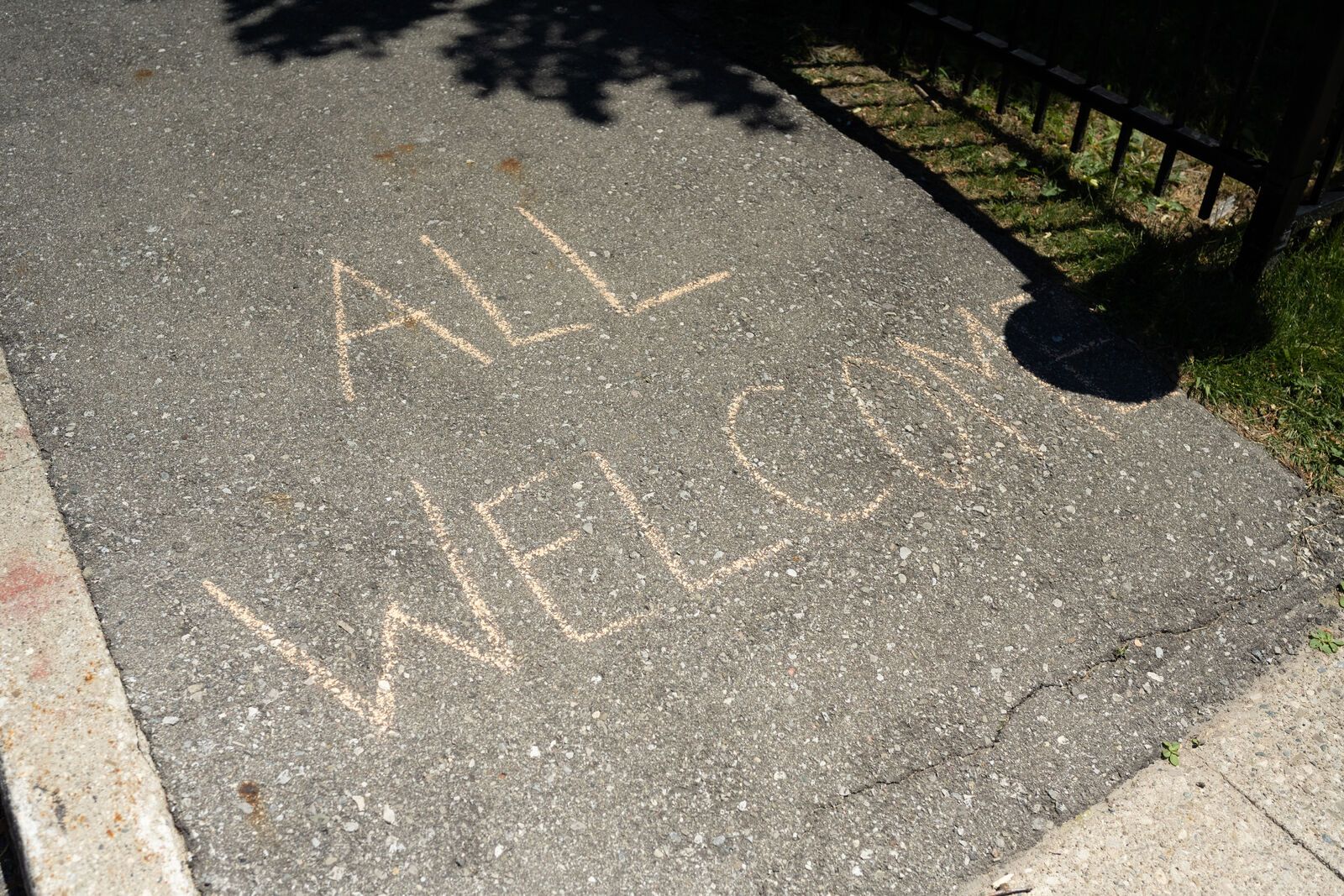 Chalk on pavement that reads "ALL WELCOME"